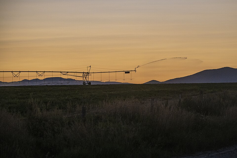 A center pivot irrigating a field at sunset